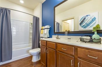 A bathroom with blue and white walls and a white toilet next to a tub with a shower
